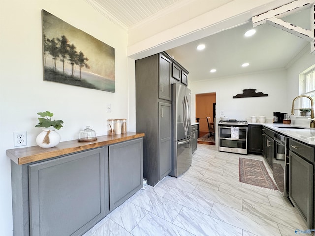 kitchen featuring marble finish floor, crown molding, recessed lighting, appliances with stainless steel finishes, and a sink