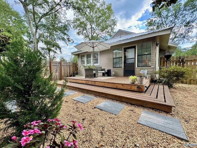 rear view of property with metal roof, fence, and a deck