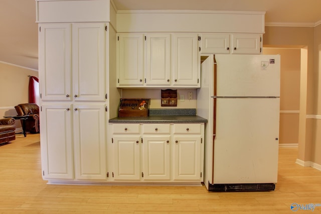 kitchen featuring ornamental molding, dark countertops, freestanding refrigerator, and white cabinets