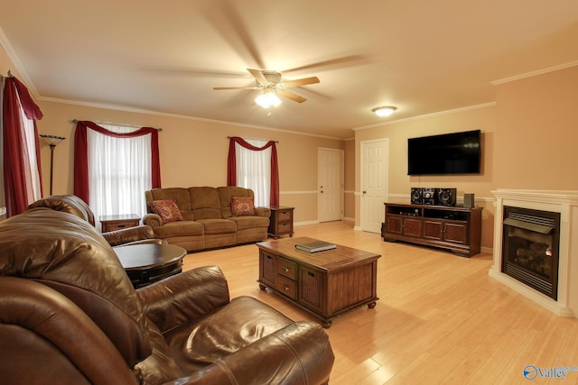 living area featuring light wood-style flooring, a fireplace, ornamental molding, and ceiling fan