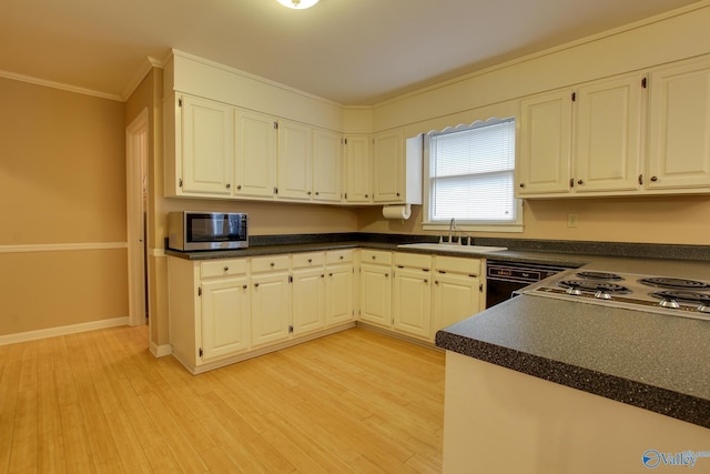 kitchen featuring dark countertops, light wood-style flooring, stainless steel microwave, and a sink