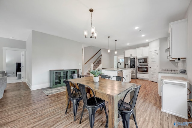 dining space featuring sink, an inviting chandelier, and light hardwood / wood-style flooring