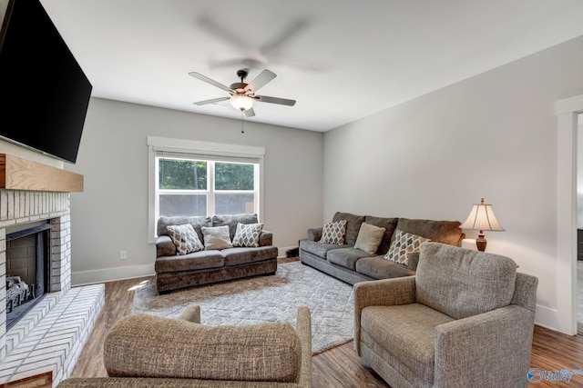 living room featuring hardwood / wood-style flooring, a brick fireplace, and ceiling fan