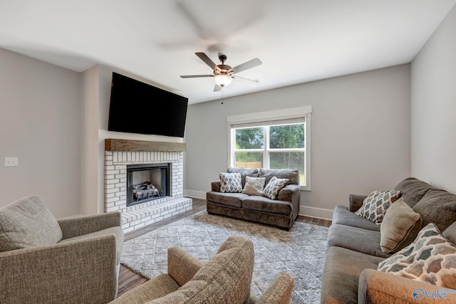 living room featuring ceiling fan, light wood-type flooring, and a brick fireplace