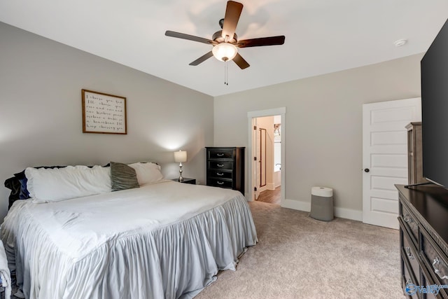 bedroom with ceiling fan, light colored carpet, and ensuite bathroom