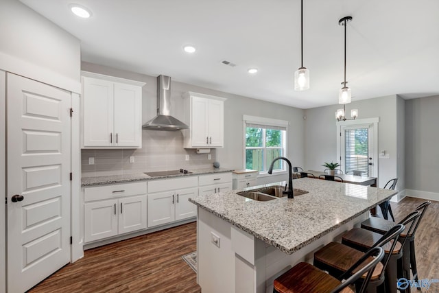 kitchen featuring black electric stovetop, dark wood-type flooring, wall chimney exhaust hood, tasteful backsplash, and sink