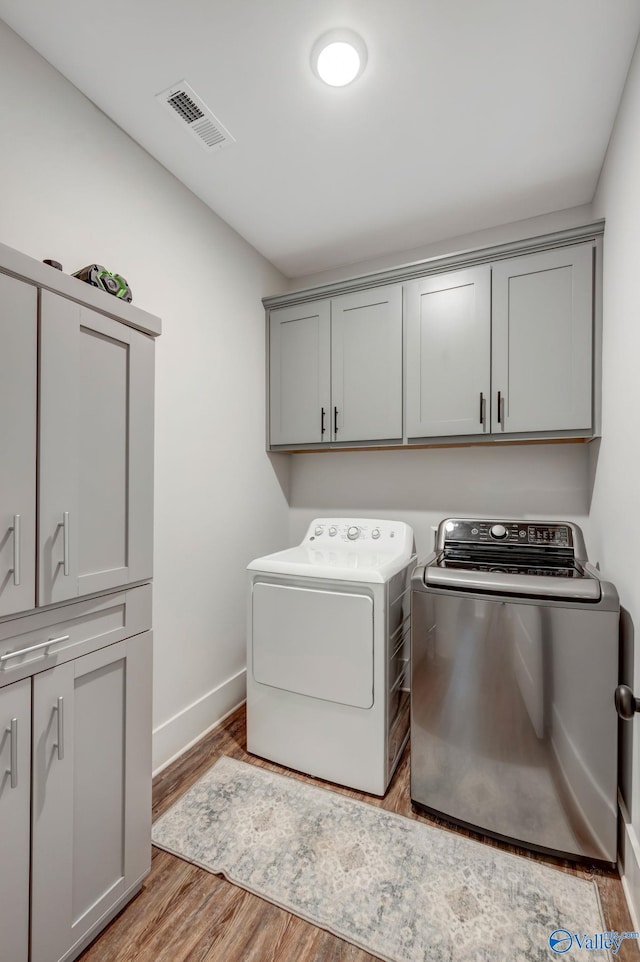 laundry room with light wood-type flooring, cabinets, and independent washer and dryer