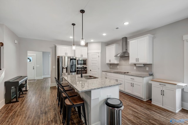 kitchen with dark wood-type flooring, wall chimney exhaust hood, tasteful backsplash, sink, and stainless steel appliances