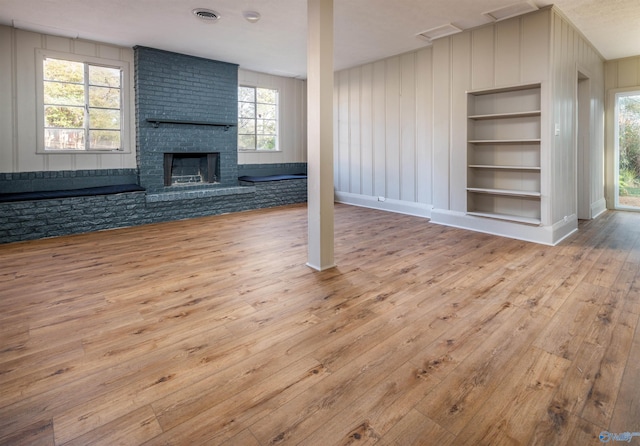 1002 Woodbine Rd, Madison, AL 35758 - unfurnished living room with wood-type flooring, a brick fireplace, visible vents, and built in features