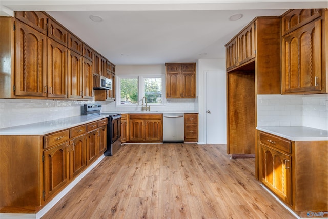 1002 Woodbine Rd, Madison, AL 35758 - kitchen with light wood finished floors, a sink, decorative backsplash, brown cabinetry, and appliances with stainless steel finishes