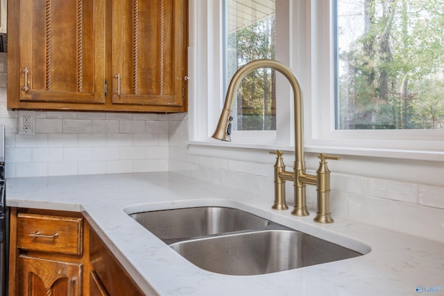 1002 Woodbine Rd, Madison, AL 35758 - details with backsplash, brown cabinetry, light stone counters, and a sink