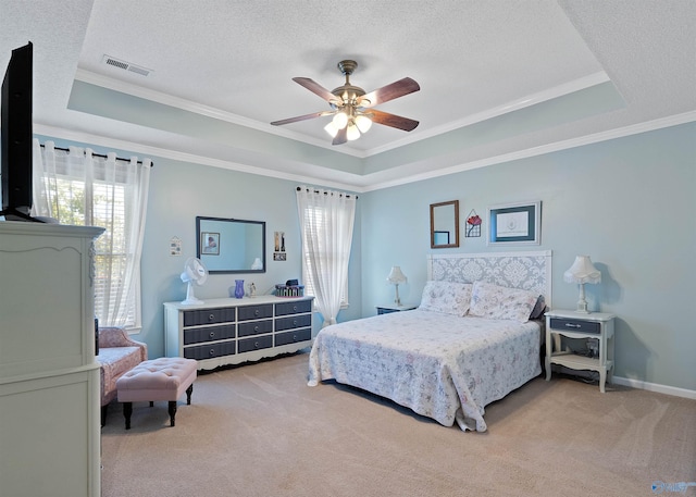 carpeted bedroom featuring ornamental molding, a tray ceiling, and a textured ceiling