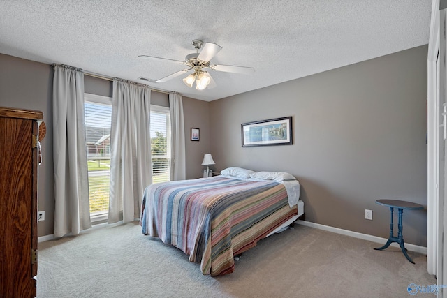 carpeted bedroom with baseboards, ceiling fan, and a textured ceiling