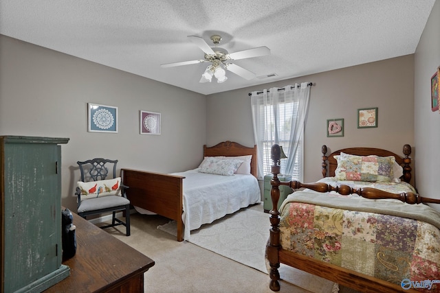 carpeted bedroom featuring visible vents, a ceiling fan, and a textured ceiling