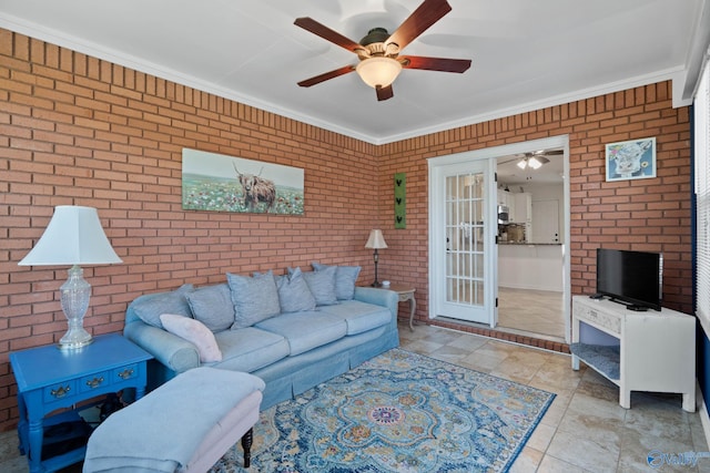 tiled living area featuring crown molding, ceiling fan, and brick wall