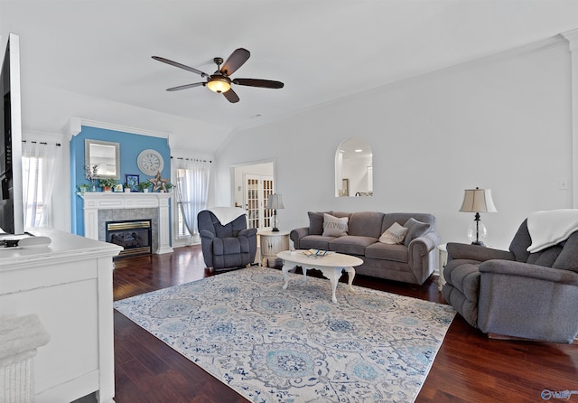 living area with ornamental molding, a ceiling fan, dark wood finished floors, vaulted ceiling, and a tile fireplace