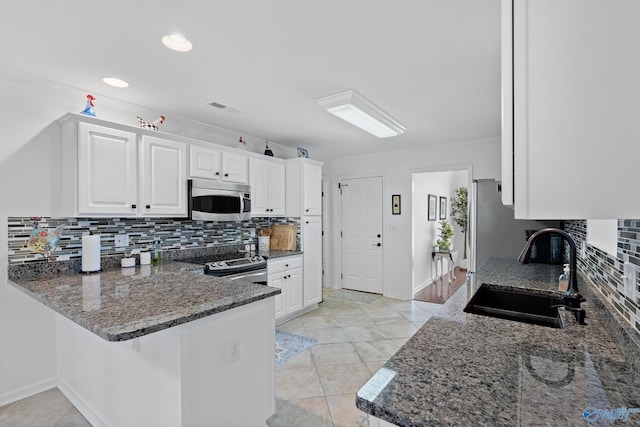 kitchen with visible vents, white cabinets, a sink, stainless steel appliances, and backsplash