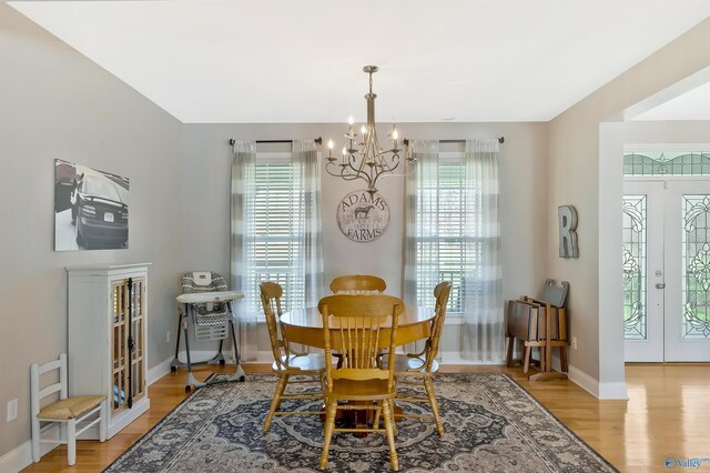 dining area with a healthy amount of sunlight, baseboards, wood finished floors, and a notable chandelier
