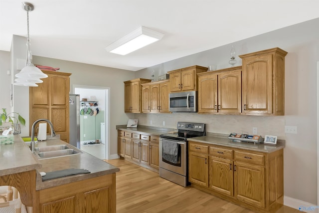 kitchen featuring tasteful backsplash, stainless steel appliances, light wood-style flooring, and a sink