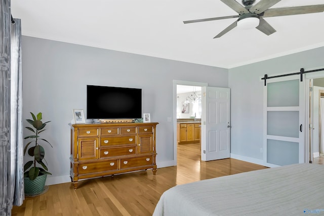bedroom with wood finished floors, a barn door, crown molding, and baseboards