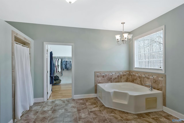 full bathroom featuring baseboards, a notable chandelier, a garden tub, and a walk in closet