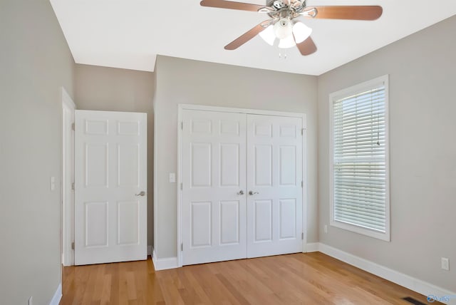 unfurnished bedroom featuring baseboards, a ceiling fan, light wood-style floors, and a closet