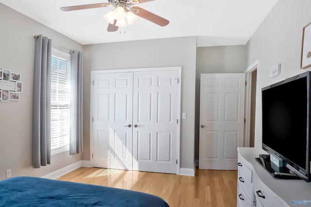 bedroom featuring ceiling fan, a closet, light wood finished floors, and baseboards