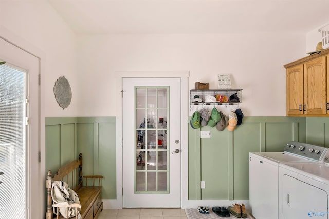 clothes washing area with washer and dryer, cabinet space, wainscoting, and a decorative wall