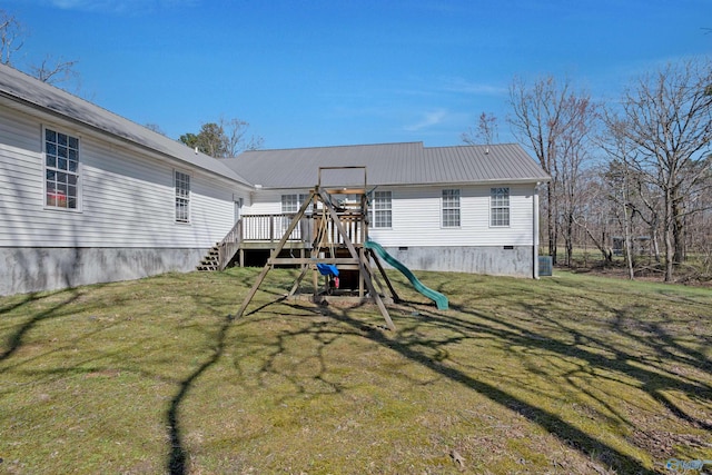view of playground featuring a lawn, a deck, and stairs