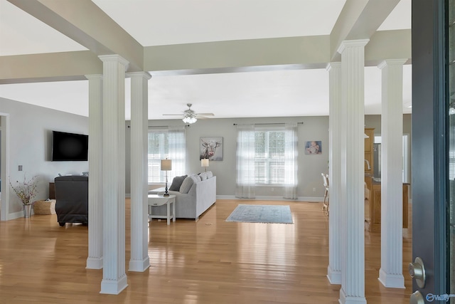 entryway with a ceiling fan, baseboards, light wood-style flooring, and ornate columns