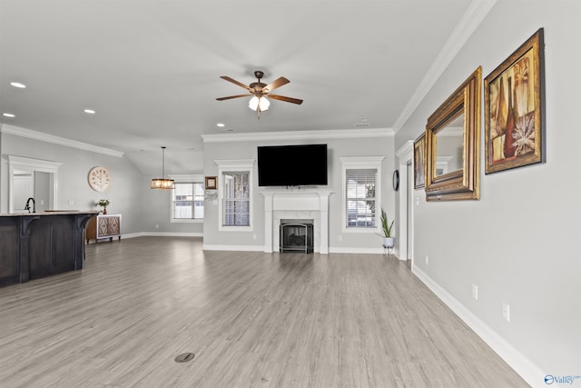 unfurnished living room featuring ceiling fan, a fireplace, crown molding, and light hardwood / wood-style flooring