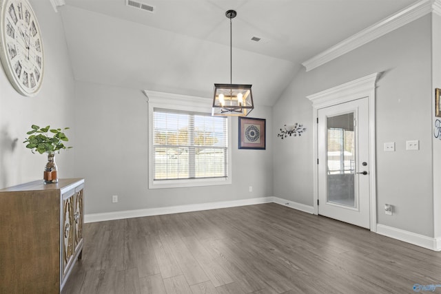 unfurnished dining area with ornamental molding, dark wood-type flooring, vaulted ceiling, and an inviting chandelier