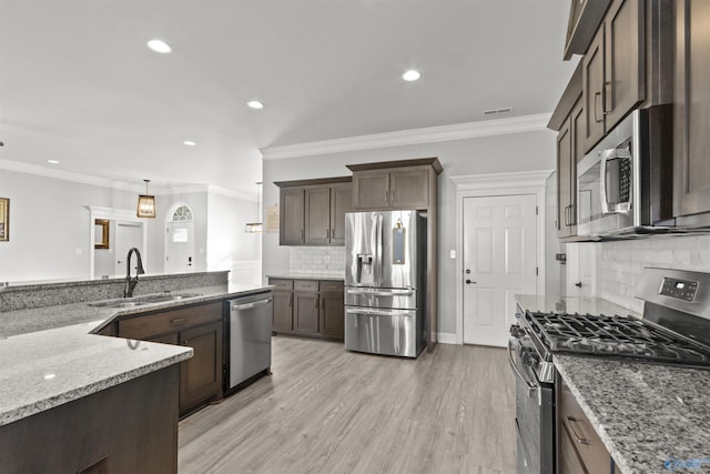 kitchen featuring light stone counters, stainless steel appliances, sink, pendant lighting, and light hardwood / wood-style floors