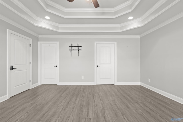 spare room featuring ceiling fan, wood-type flooring, crown molding, and a tray ceiling