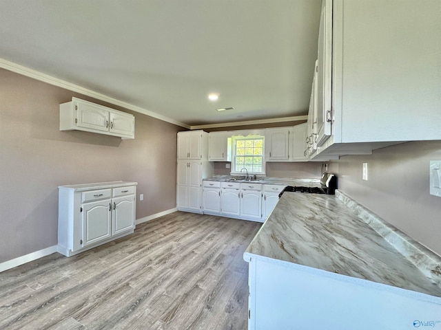 kitchen featuring light hardwood / wood-style flooring, white cabinets, range with gas stovetop, sink, and ornamental molding