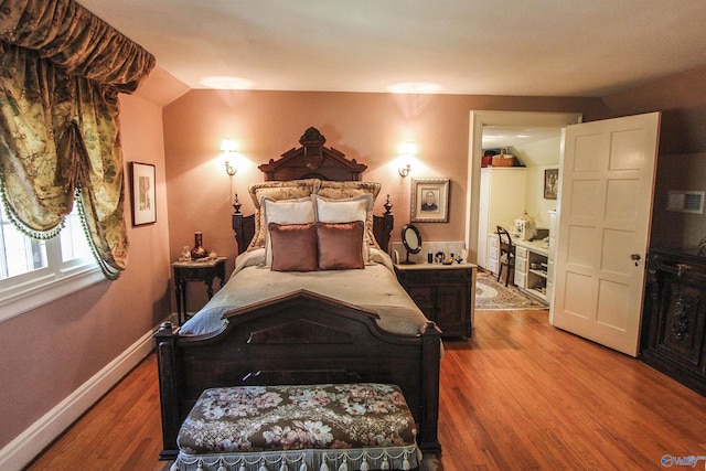 bedroom featuring vaulted ceiling, wood finished floors, and baseboards