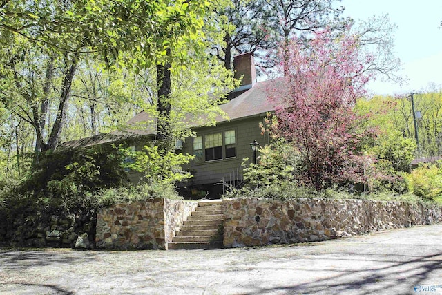 view of side of home featuring stairway and a chimney