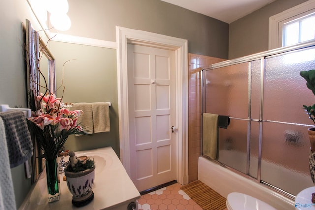 full bathroom featuring tile patterned flooring, toilet, bath / shower combo with glass door, and vanity