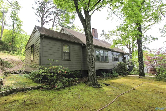 view of side of home with a lawn and a chimney