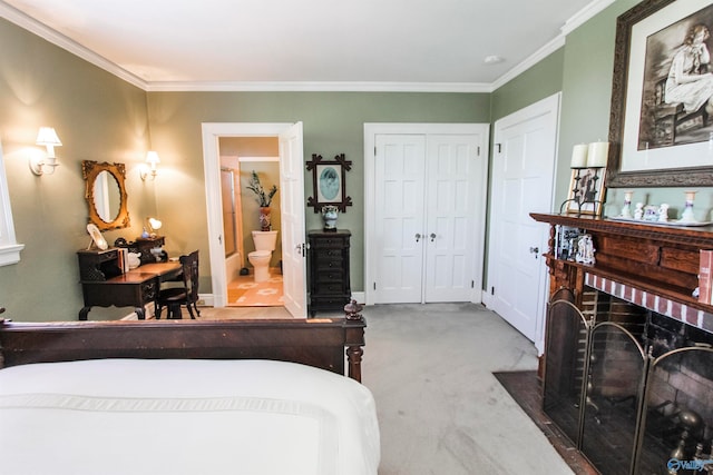 carpeted bedroom with ornamental molding, a closet, and ensuite bath