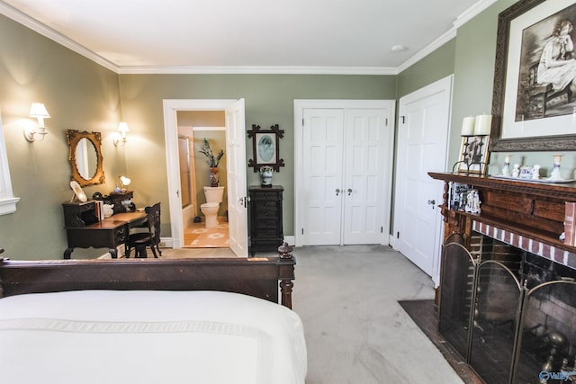 carpeted bedroom featuring ensuite bath, crown molding, a fireplace, and a closet