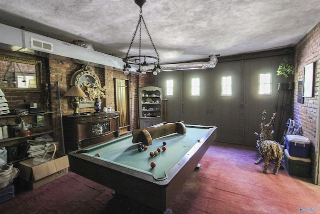 game room with brick wall, pool table, and a textured ceiling