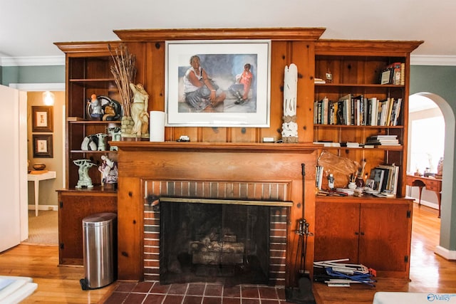 room details with crown molding, wood-type flooring, and a brick fireplace