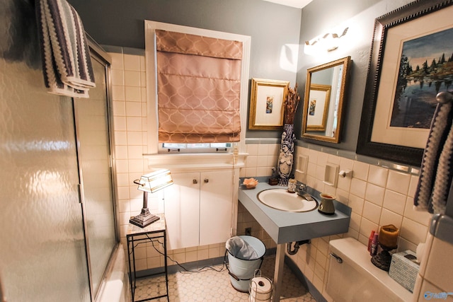 bathroom with sink, walk in shower, tile patterned floors, and tile walls