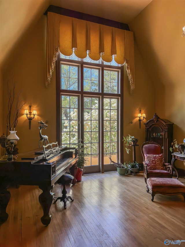 sitting room featuring high vaulted ceiling and wood-type flooring