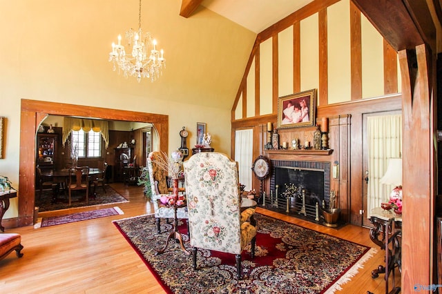 interior space with hardwood / wood-style floors, high vaulted ceiling, a brick fireplace, and a chandelier