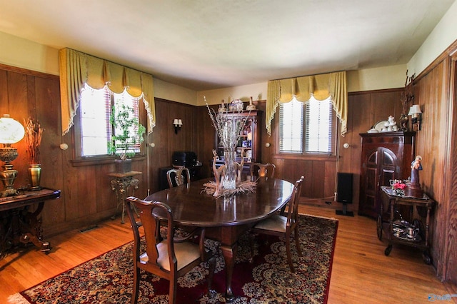 dining space with wooden walls and light hardwood / wood-style flooring