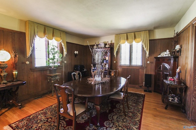 dining area featuring wood finished floors, visible vents, and wood walls