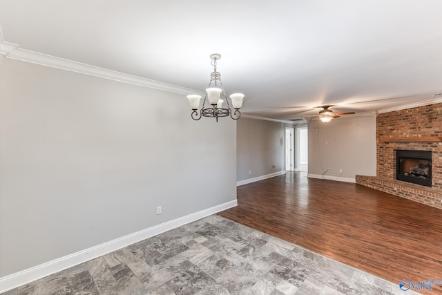 unfurnished living room with a brick fireplace, wood-type flooring, crown molding, and ceiling fan with notable chandelier