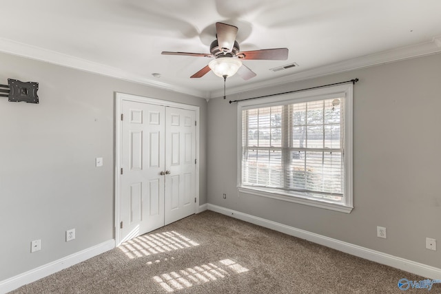 unfurnished bedroom featuring ceiling fan, ornamental molding, a closet, and carpet floors